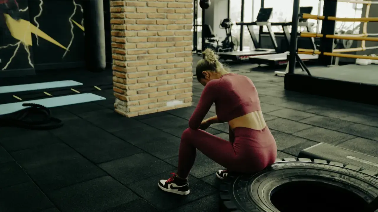 mulher sentada, sentindo calor por falta de climatizador para academia.